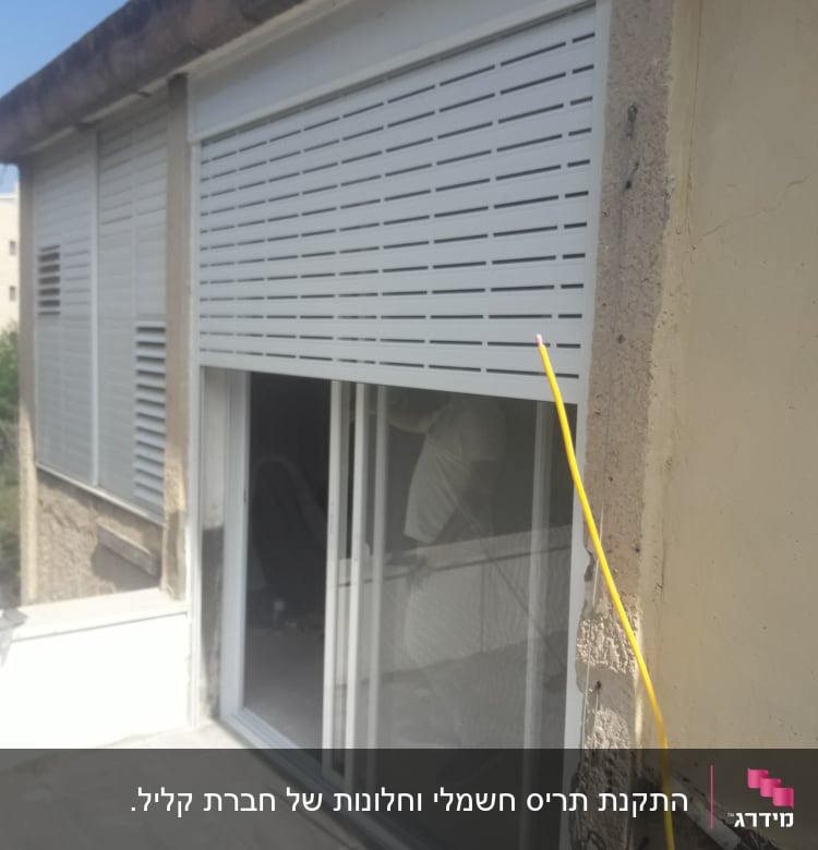 תריסי אלומיניום לבנים על חלון זכוכית